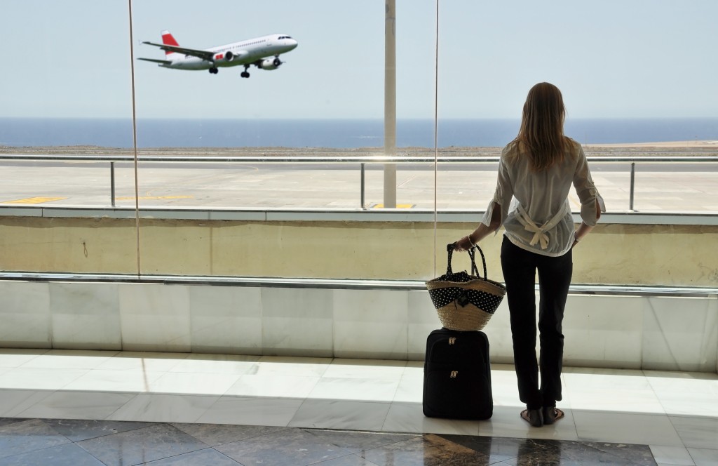 Girl at the airport window looking to the ocean