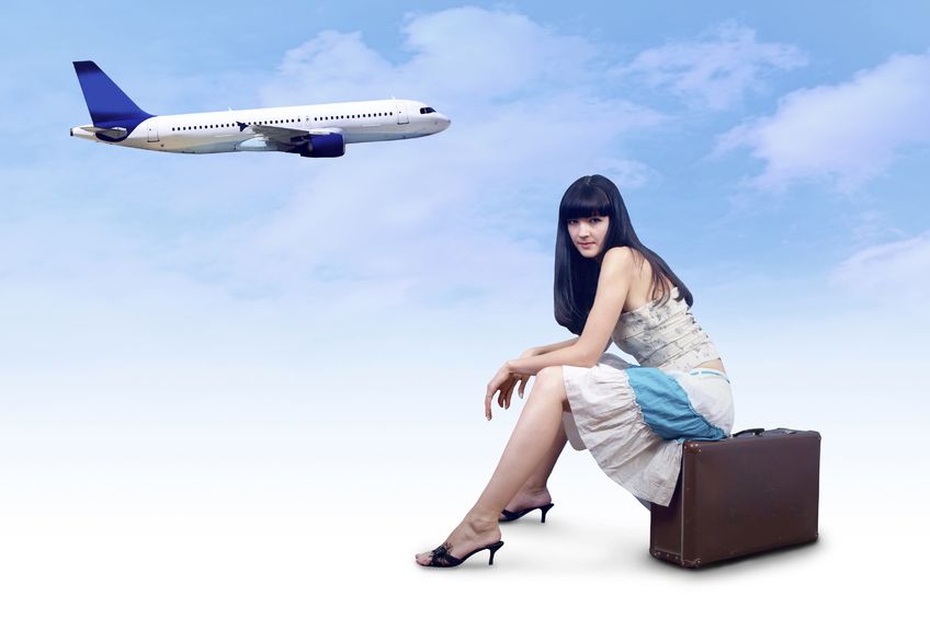 woman sitting on suitcase with plane in background