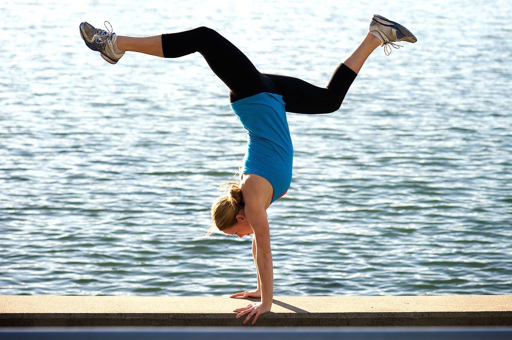 woman doing handstand in front of body of water