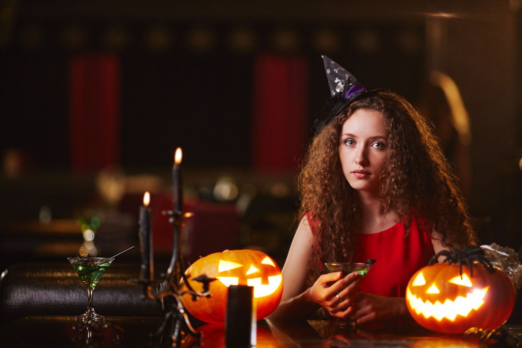 Beautiful witch with martini looking at camera