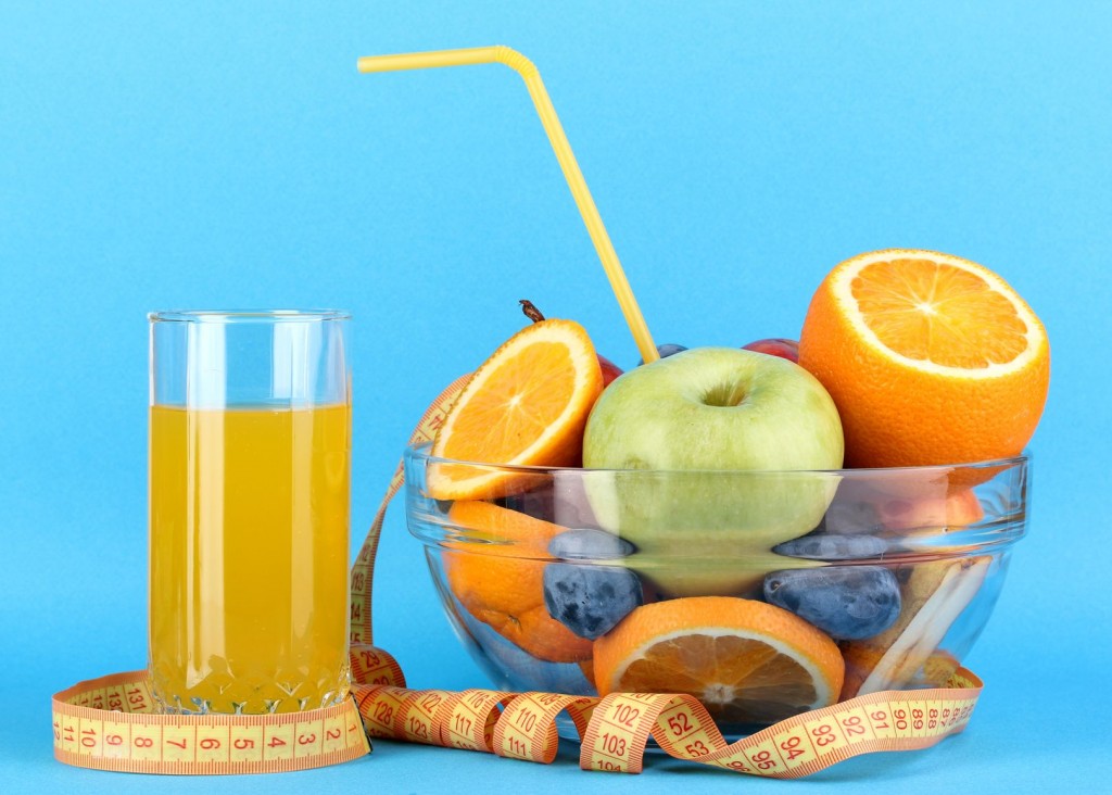 Glass bowl with fruit for diet and juice on blue background