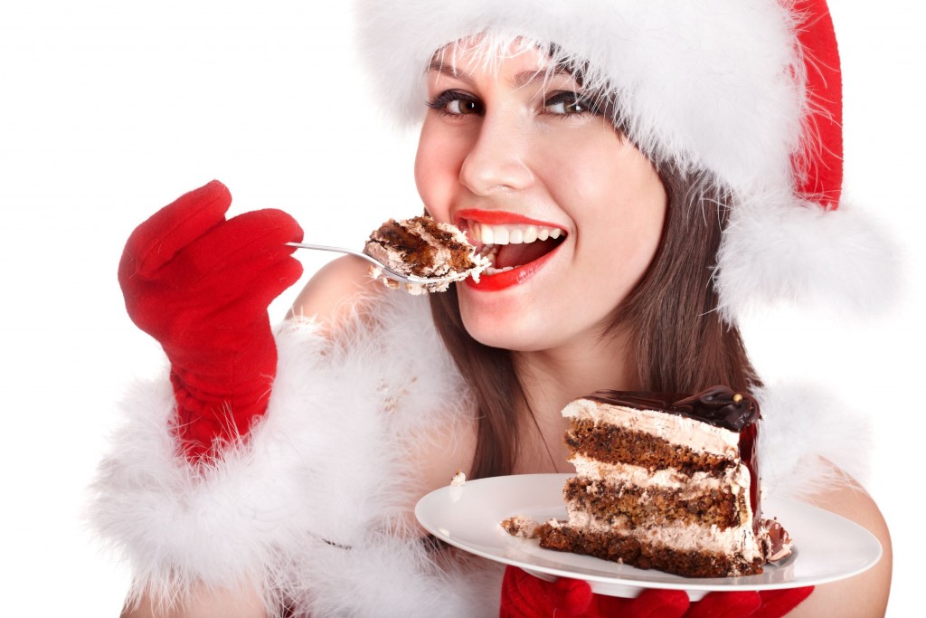 Girl in Santa hat eat cake on plate . Isolated