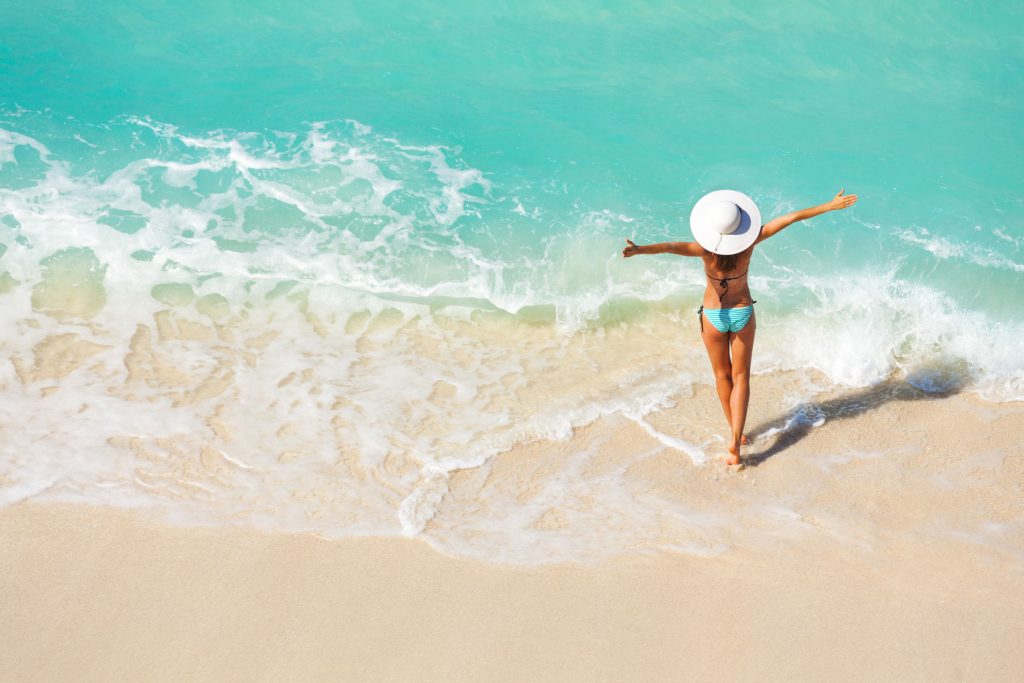 woman with arms spread open on sand beach